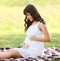 Lovely pregnant woman in white dress with wildflowers in summer