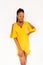 Lovely pretty african woman with dreadlocks hairstyle in yellow fashionable dress isolated on beo background