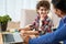 Lovely pupil. Joyful little latin school boy doing homework together with his father, using laptop while sitting at the