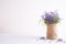 Lovely purple flower in sack vase on white wooden table