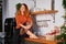 A lovely red-haired girl sits on the roofing cloth in a stylish cozy kitchen decorated for Christmas