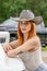 A Lovely Red Headed Cowgirl Poses In A Country Western Setting Outdoors Against Her Truck