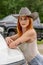 A Lovely Red Headed Cowgirl Poses In A Country Western Setting Outdoors Against Her Truck