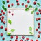 Lovely ripe sweet cherry with leaves around blank white chalkboard, top view.