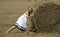 Lovely smiling woman plying with haystack outdoors