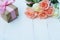 Lovely soft orange pink color rose tied by pink ribbon and brown gift box on white wood table background, sweet valentine present