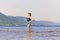 Lovely sporty mature woman stands and splashes water on the beach on the Volga river on a summer sunny day against the background