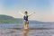 Lovely sporty mature woman stands and splashes water on the beach on the Volga river on a summer sunny day against the background