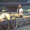 Lovely teen girl with the bike sits on the waterfront