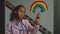 Lovely teenage girl painting rainbow on window