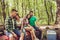 So lovely! Two married couples are resting in a campgroung in summer sunny forest, sitting and cuddling