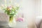 Lovely wild flowers bunch in glass vase on table in light living room , Home decoration