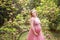 Lovely woman expecting baby in beautiful dress background of blossoming magnolia and greenery