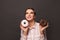 Lovely woman holding doughnut, smiling and looking up on black background. Diet, dieting, junk food, slimming and weight loss