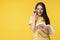 Lovely woman look tricky taking off funny eye glasses while reading book in her hand over isolated yellow background.