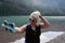 Lovely young adult woman fixes and primps her hair before taking a selfie after hiking Avalanche Lake in Glacier National Park