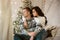 Lovely young couple beautiful woman and handsome man both wearing cozy sweaters hugging on the sofa decorated for celebrating the