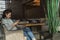 Lovely young girl is sitting alone in an empty cafeteria or restaurant and is surfing in the phone. Horizontal view. Side view