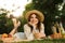 Lovely young girl in summer hat having a picnic at the park, laying on a grass