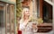 Lovely young lady in summer hat resting in open-air cafe propped face with hand and waiting friend. Outdoor portrait of