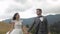 Lovely young newlyweds bride groom walking on mountain slope, holding hands, wedding couple family