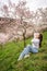 Lovely young woman in a blooming pink and white garden Petrin in Prague, spring time in Europe