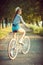 Lovely young woman in a hat riding a bicycle in a park