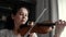 Lovely young woman plays the violin at home, close-up in slow motion