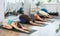 Lovers of active lifestyle on yoga mat perform doing version of child pose in gym