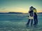 Lovers hold each other stay on ice in frozen lagoon and watch sun