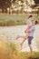 Lovers in a lake. Young couple in love sitting on the park ground near the water while these young man playing guitar in sunset