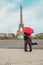 Lovers with a red umbrella near the Eiffel Tower in Paris. Selective focus