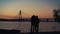 Lovers silhouette watching sunset at river shore. Beautiful evening clear sky.