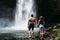 Lovers at the waterfall, rear view. Couple admiring a beautiful waterfall in Indonesia. Couple on vacation in Bali. Honeymoon trip