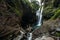 Lovers at the waterfall, rear view. Couple admiring a beautiful waterfall in Indonesia. Couple on vacation in Bali. Honeymoon trip