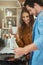 She loves watching him cook. an attractive young woman watching her boyfriend cook in their kitchen.