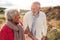 Loving Active Senior Couple Walking Arm In Arm Through Sand Dunes On Winter Beach Vacation