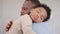 Loving African American dad embracing baby and baby girl sleeping on stepfather shoulder. Happy family with pleasure spending time