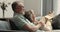 Loving aged husband hug shoulders of wife relaxing on sofa