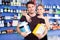 Loving athletic couple holding plastic jars of sport food supplements in shop interior