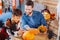 Loving bearded father joining his cute son coloring pumpkins for Halloween party