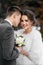 Loving and beautiful bride and groom stand in an embrace in the winter forest. Vertical frame