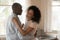 Loving biracial couple dance in kitchen celebrating anniversary