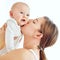Loving, caring and affectionate mother kissing and bonding with her baby. Female embracing motherhood holding her baby