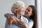 Loving cheerful grownup daughter hugs elderly mother laughing having fun