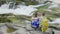 A loving couple admires the beautiful mountain river. They sit side by side on a rock, water is bubbling around