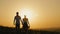 Loving couple - brave young man and beautiful girl at sunset silhouette, over the sun