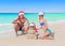 Loving couple and funny sandy Christmas snowman in santa hats at sea beach