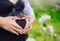 Loving couple with heart shape hands around pregnant belly