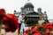 Loving couple hugs against a background of red flowers and vintage architecture.